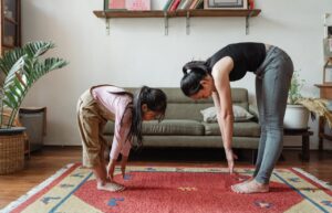 A woman and a young child are stretching and practice touching their toes